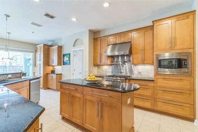 kitchen with decorative backsplash, visible vents, stainless steel appliances, a center island, and under cabinet range hood
