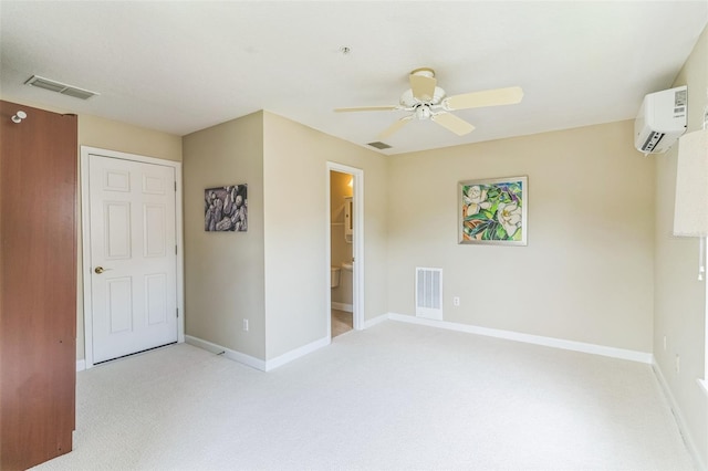 empty room featuring visible vents, a wall unit AC, light carpet, and ceiling fan