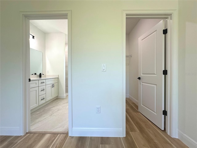 unfurnished bedroom with light wood-type flooring, baseboards, and ensuite bathroom