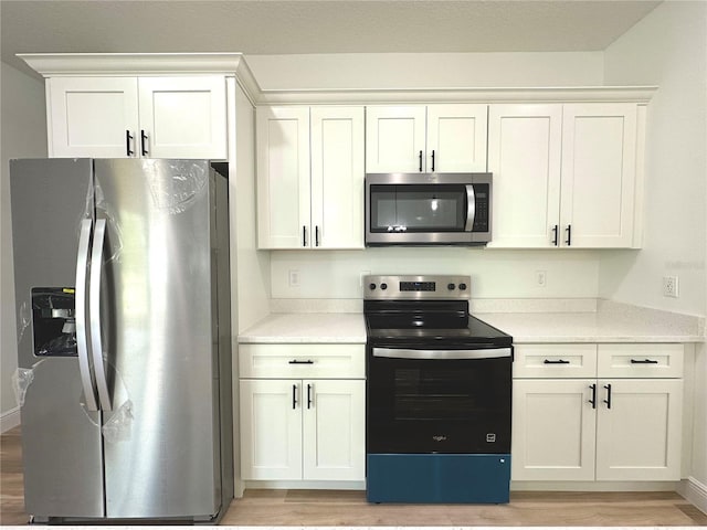 kitchen featuring light countertops, white cabinets, appliances with stainless steel finishes, and light wood finished floors