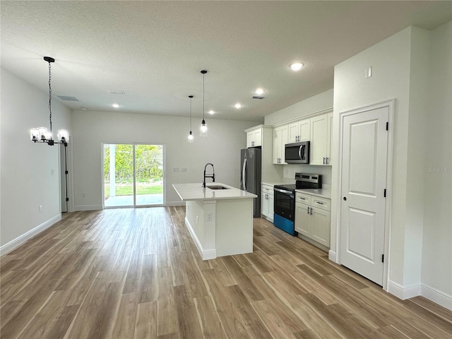kitchen featuring stainless steel appliances, baseboards, a sink, and light wood-type flooring