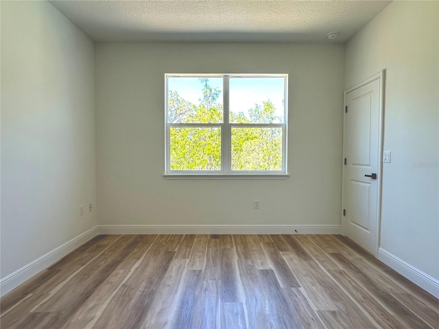 unfurnished room with baseboards, a textured ceiling, and wood finished floors