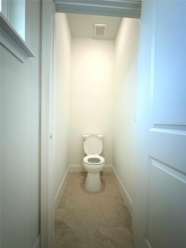bathroom with baseboards, toilet, and visible vents