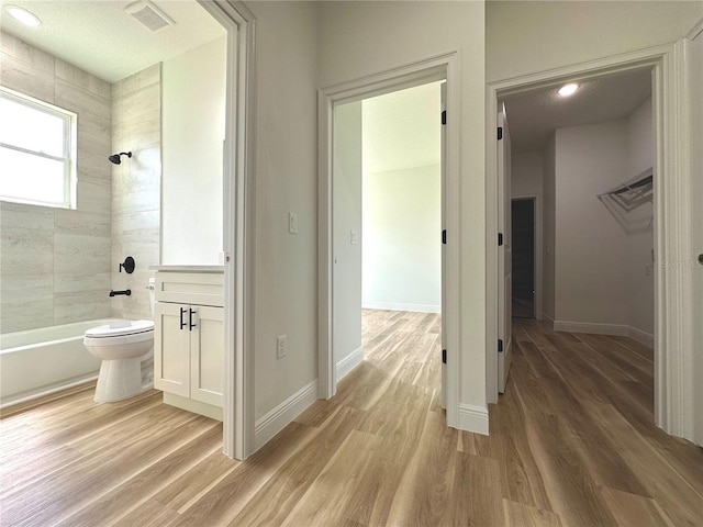 full bathroom featuring shower / tub combination, toilet, baseboards, wood finished floors, and visible vents