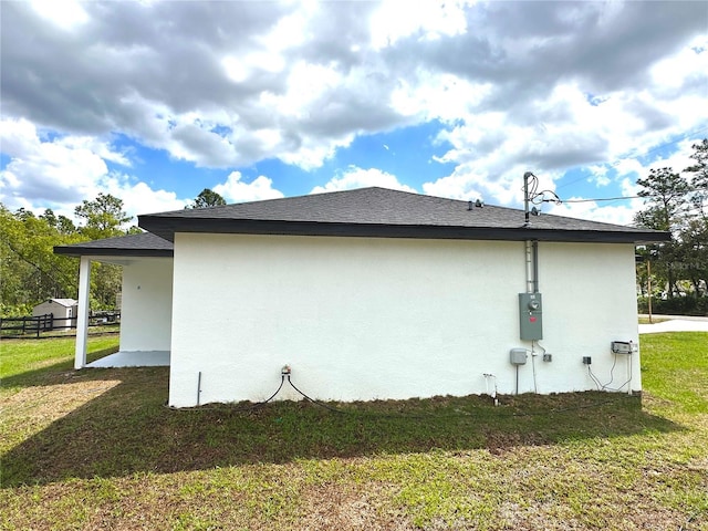 view of side of home with a lawn, fence, and stucco siding