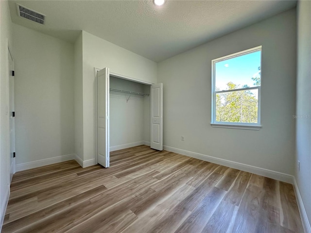 unfurnished bedroom featuring baseboards, visible vents, and wood finished floors