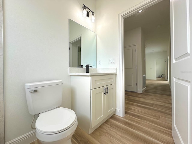 bathroom featuring vanity, baseboards, toilet, and wood finished floors