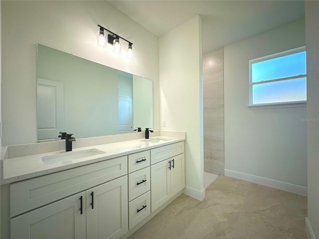 bathroom with a walk in shower, double vanity, baseboards, and a sink