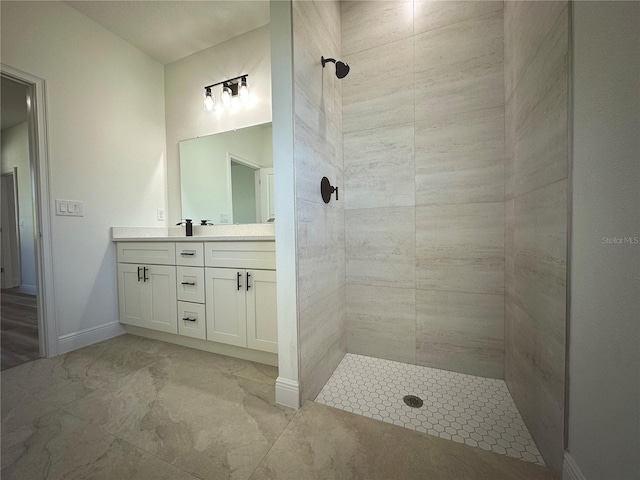 full bath with vanity, baseboards, and tiled shower