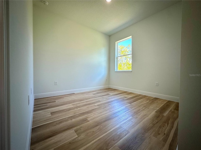 empty room featuring baseboards, a textured ceiling, and light wood-type flooring