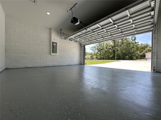 garage featuring concrete block wall, a garage door opener, and electric panel