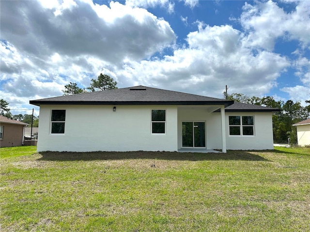 rear view of property featuring a lawn, stucco siding, and roof with shingles