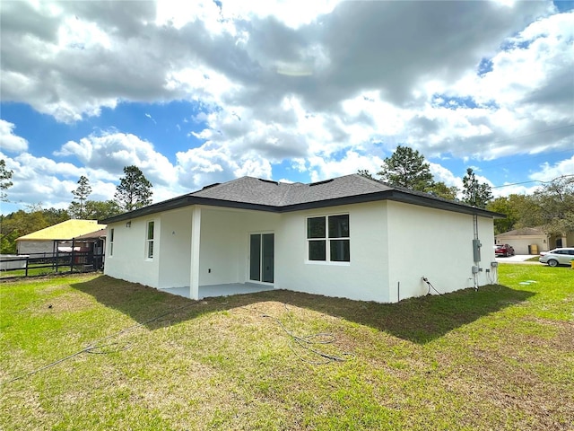 back of property featuring fence, stucco siding, a shingled roof, a patio area, and a yard