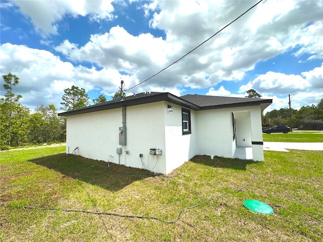 view of property exterior with stucco siding and a yard