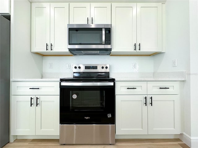 977 W Anderson Ln, Citrus Springs, FL 34434 - kitchen featuring stainless steel appliances, light wood-type flooring, white cabinets, and tasteful backsplash