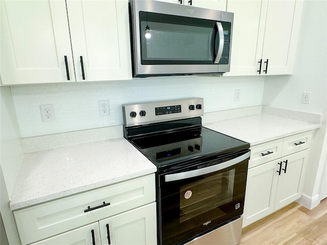 977 W Anderson Ln, Citrus Springs, FL 34434 - kitchen with appliances with stainless steel finishes, light wood finished floors, white cabinets, light stone counters, and decorative backsplash