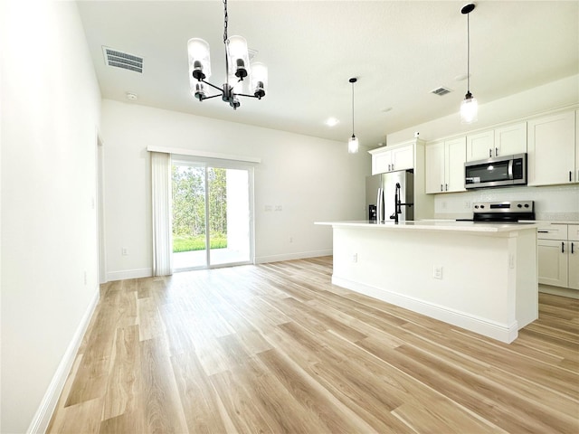 977 W Anderson Ln, Citrus Springs, FL 34434 - kitchen with stainless steel appliances, light wood-style floors, an island with sink, a chandelier, and light countertops