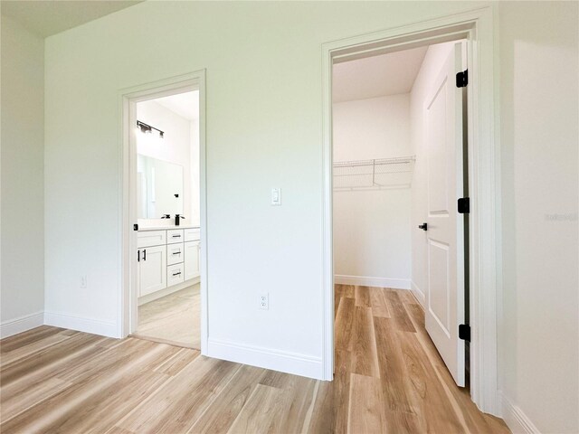 977 W Anderson Ln, Citrus Springs, FL 34434 - unfurnished bedroom with light wood-style floors, a closet, a walk in closet, and baseboards