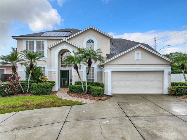 10915 Piping Rock Cir, Orlando, FL 32817 - view of front facade with roof mounted solar panels, a garage, fence, stucco siding, and driveway