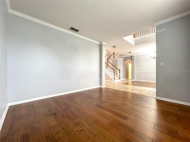 10915 Piping Rock Cir, Orlando, FL 32817 - empty room featuring stairway, crown molding, visible vents, hardwood / wood-style floors, and arched walkways