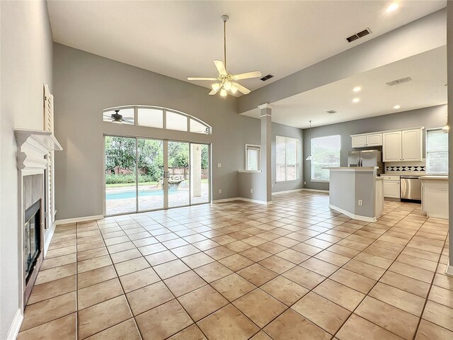 10915 Piping Rock Cir, Orlando, FL 32817 - unfurnished living room featuring light tile patterned floors, visible vents, baseboards, ceiling fan, and a tile fireplace
