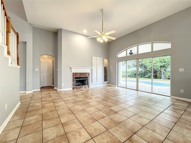 10915 Piping Rock Cir, Orlando, FL 32817 - unfurnished living room featuring a towering ceiling, baseboards, light tile patterned floors, ceiling fan, and a tile fireplace