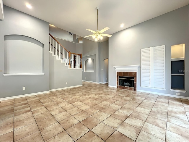 10915 Piping Rock Cir, Orlando, FL 32817 - unfurnished living room with baseboards, a tiled fireplace, ceiling fan, a towering ceiling, and stairs
