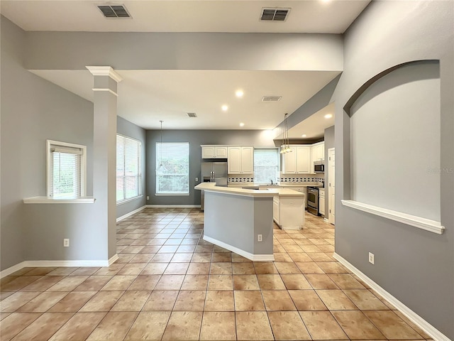 10915 Piping Rock Cir, Orlando, FL 32817 - kitchen featuring white cabinetry, visible vents, a center island, appliances with stainless steel finishes, and light countertops