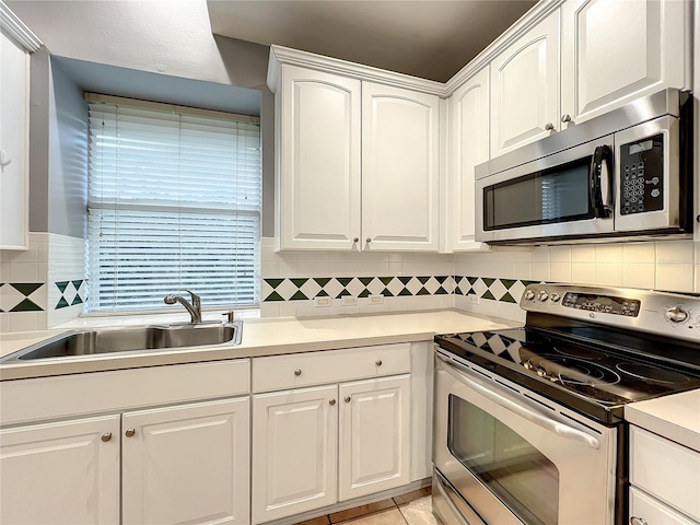 10915 Piping Rock Cir, Orlando, FL 32817 - kitchen with white cabinets, a sink, light countertops, stainless steel appliances, and backsplash