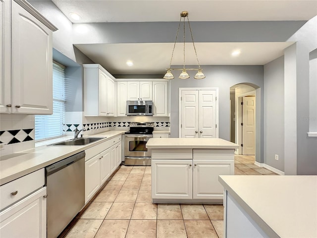 10915 Piping Rock Cir, Orlando, FL 32817 - kitchen featuring backsplash, white cabinets, stainless steel appliances, arched walkways, and a sink