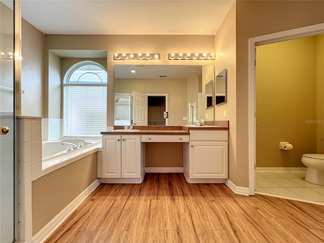 10915 Piping Rock Cir, Orlando, FL 32817 - bathroom with toilet, vanity, wood finished floors, and a garden tub