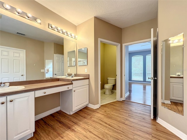 10915 Piping Rock Cir, Orlando, FL 32817 - bathroom featuring a sink, visible vents, double vanity, and wood finished floors