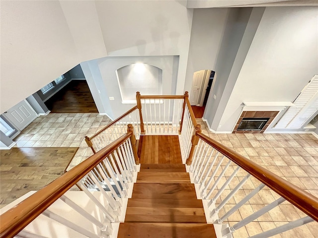 10915 Piping Rock Cir, Orlando, FL 32817 - staircase featuring a tiled fireplace, baseboards, a towering ceiling, and wood finished floors