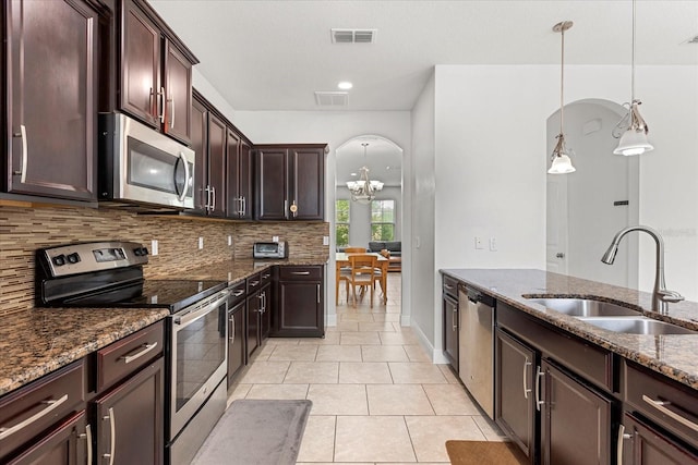 10866 Sunset Ridge Ln, Orlando, FL 32832 - kitchen with dark stone countertops, a notable chandelier, a sink, stainless steel appliances, and decorative backsplash
