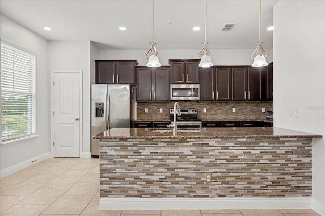 10866 Sunset Ridge Ln, Orlando, FL 32832 - kitchen featuring dark stone counters, dark brown cabinetry, visible vents, a sink, and stainless steel appliances