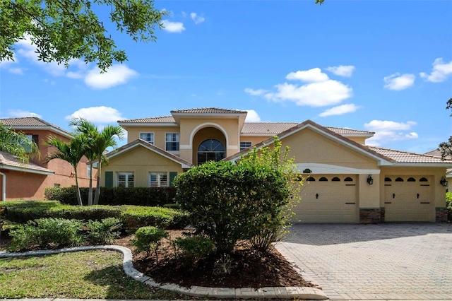 3583 Valleyview Dr, Kissimmee, FL 34746 - mediterranean / spanish house with stucco siding, a tiled roof, decorative driveway, stone siding, and an attached garage
