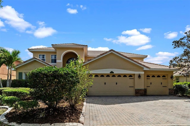 3583 Valleyview Dr, Kissimmee, FL 34746 - mediterranean / spanish house with a tile roof, decorative driveway, an attached garage, and stucco siding