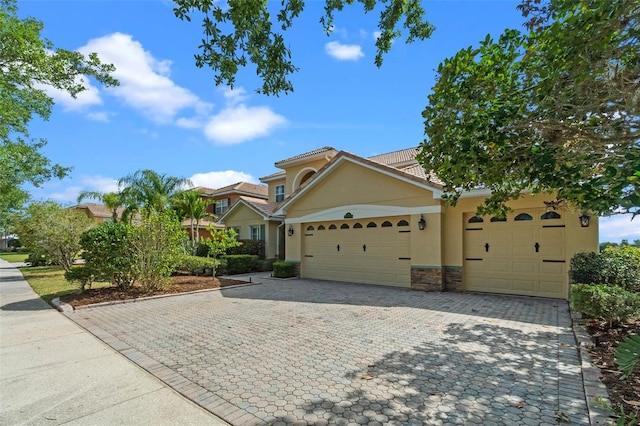 3583 Valleyview Dr, Kissimmee, FL 34746 - view of front facade featuring a tile roof, a garage, decorative driveway, stone siding, and stucco siding