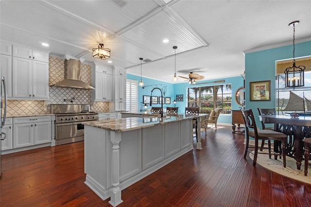 3583 Valleyview Dr, Kissimmee, FL 34746 - kitchen with light stone countertops, white cabinetry, decorative backsplash, wall chimney range hood, and range with two ovens