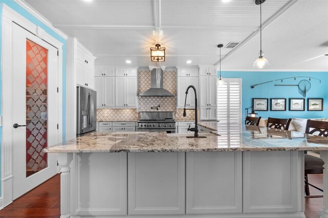 3583 Valleyview Dr, Kissimmee, FL 34746 - kitchen with a kitchen breakfast bar, tasteful backsplash, a sink, appliances with stainless steel finishes, and wall chimney exhaust hood