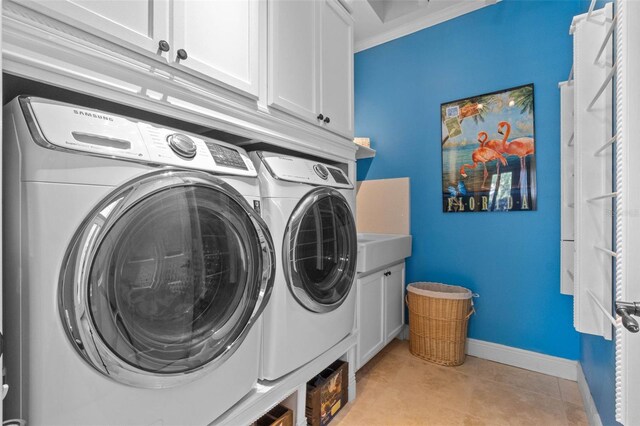 3583 Valleyview Dr, Kissimmee, FL 34746 - laundry area featuring light tile patterned flooring, cabinet space, baseboards, and washer and clothes dryer