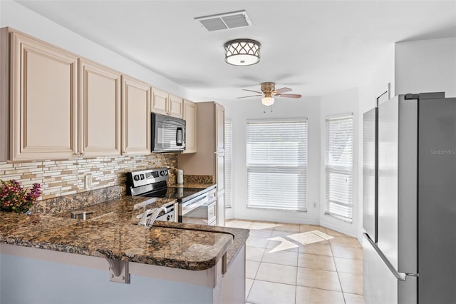 9301 Echo Run, Orlando, FL 32817 - kitchen with appliances with stainless steel finishes, cream cabinets, tasteful backsplash, a ceiling fan, and a peninsula