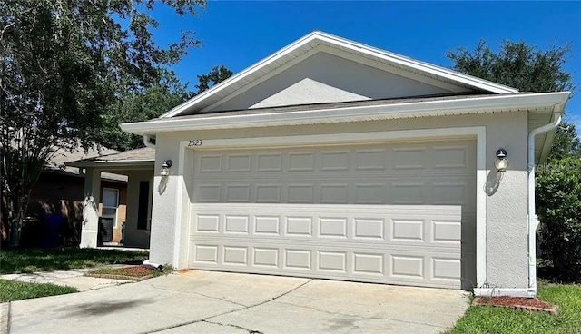 exterior space with concrete driveway, stucco siding, and a garage