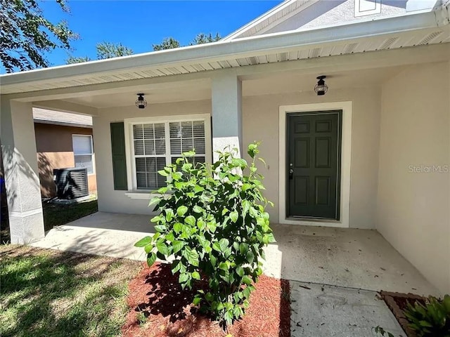 doorway to property featuring stucco siding and covered porch