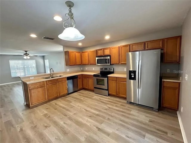 kitchen with brown cabinetry, visible vents, appliances with stainless steel finishes, a sink, and light countertops