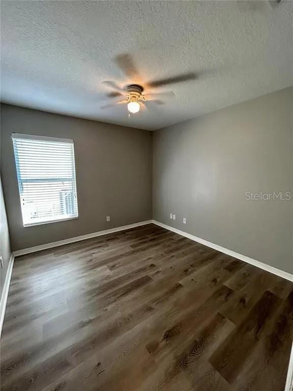 unfurnished room featuring dark wood-type flooring, a textured ceiling, baseboards, and a ceiling fan