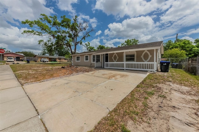 view of front facade featuring a porch, driveway, fence, and stucco siding