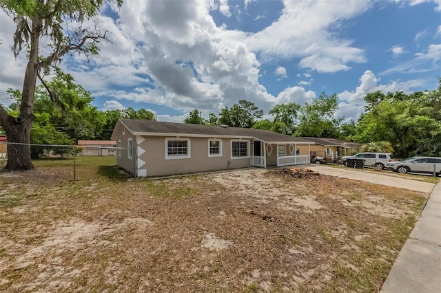 view of front of home with driveway, stucco siding, and fence
