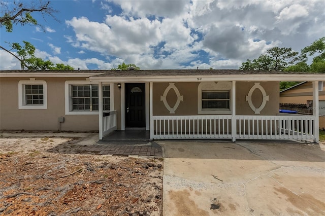ranch-style home with stucco siding and covered porch
