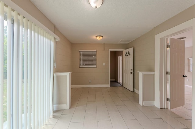 hall featuring light tile patterned floors and a textured ceiling
